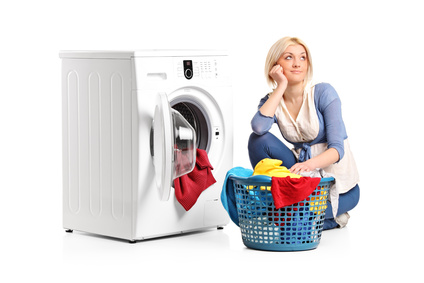 Woman in thoughts with clothes seated next to a washing machine